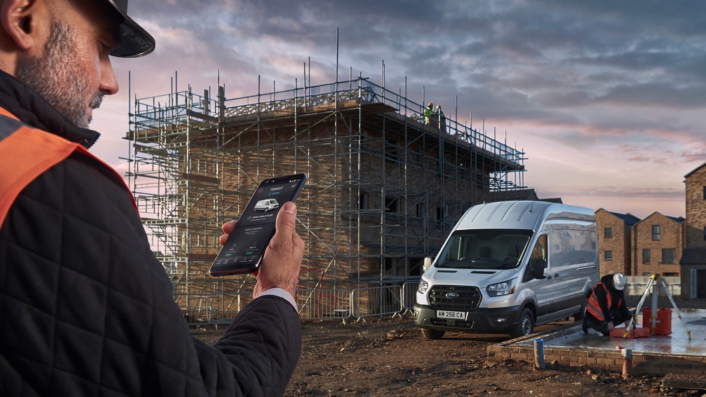 Un muratore tiene in mano uno smartphone