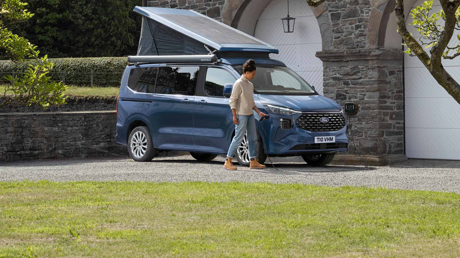 Una donna college il cavo per caricare il Ford Nugget PHEV.