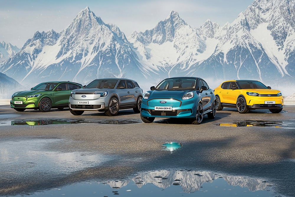 Quattro modelli Ford colorati sono affiancati su suolo bagnato davanti a montagne innevate.
