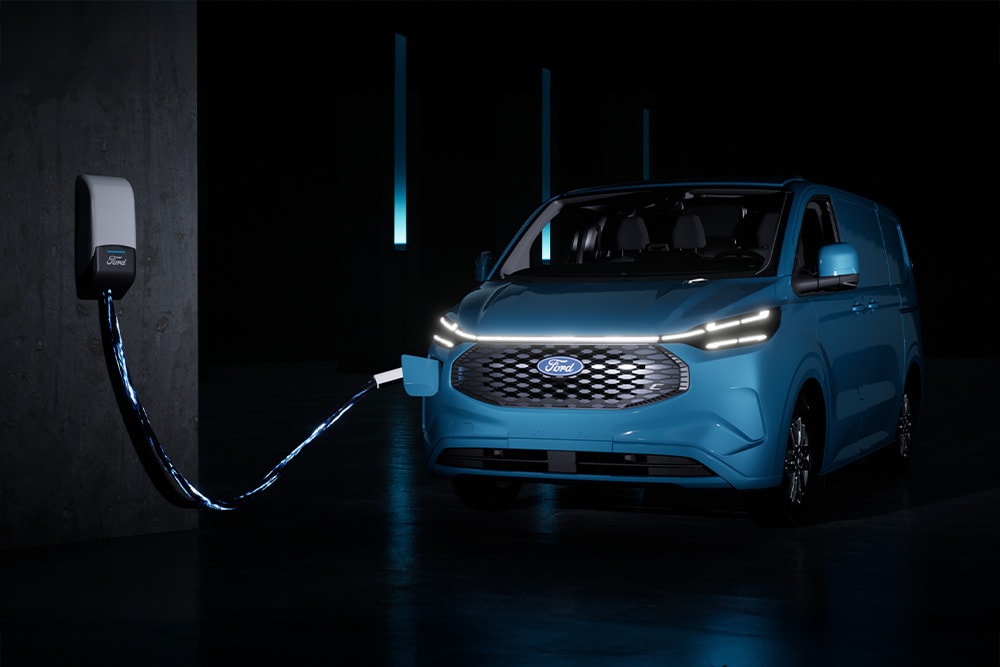 Un Ford E-Transit Custom blu in carica presso una stazione di ricarica.