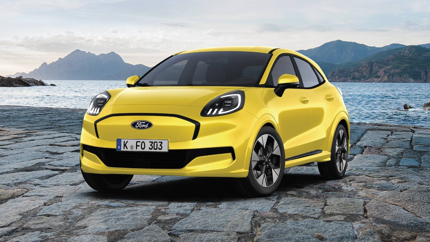 La dinamica ed elettrica Ford Puma Gen-E di colore rosso, fotografata sullo sfondo di montagne e acqua di Maiorca