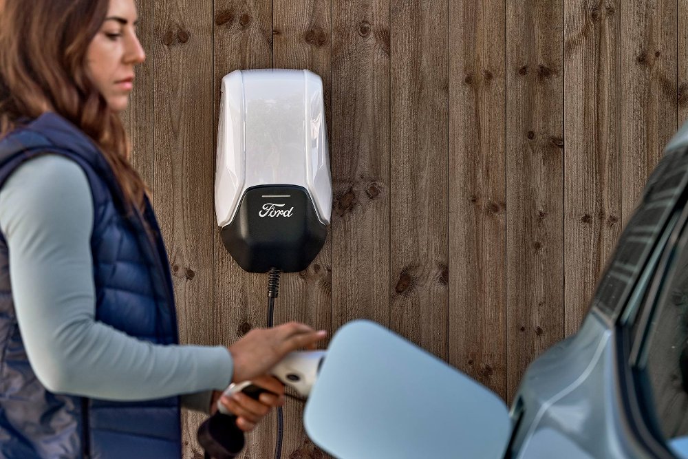 Una donna collega il nuovo Ford Explorer alla Ford Wallbox mediante un cavo di ricarica
