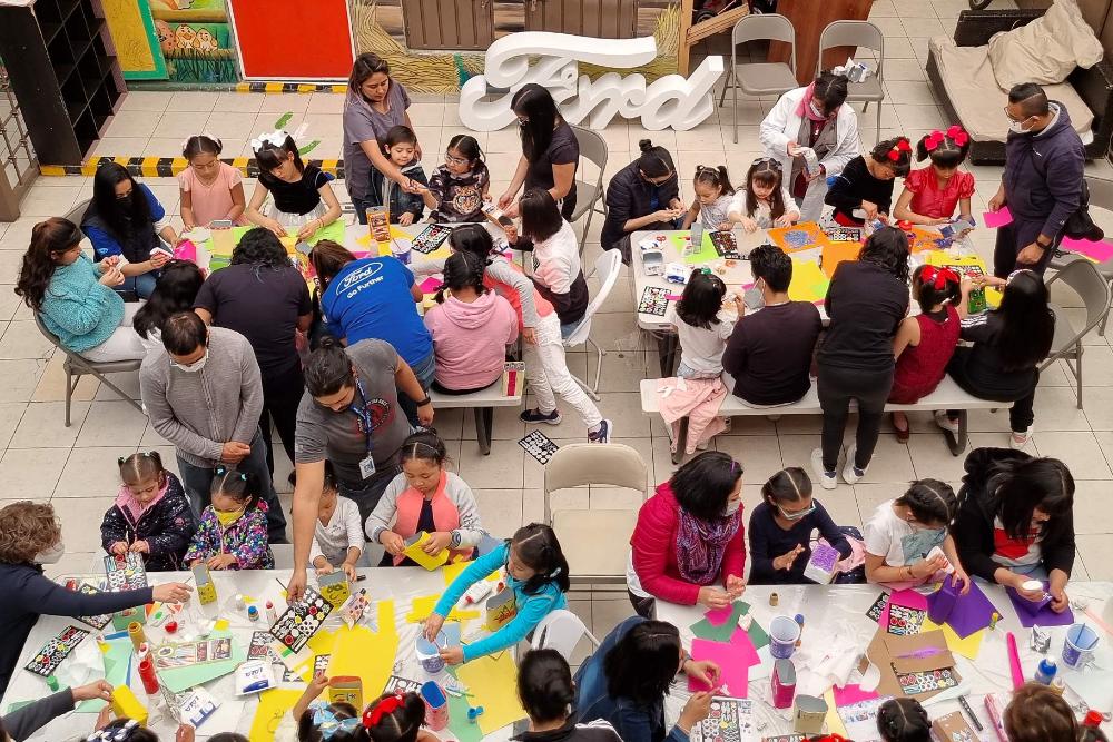 Visuale aerea su un grande gruppo di bambini che fa bricolage insieme a degli educatori