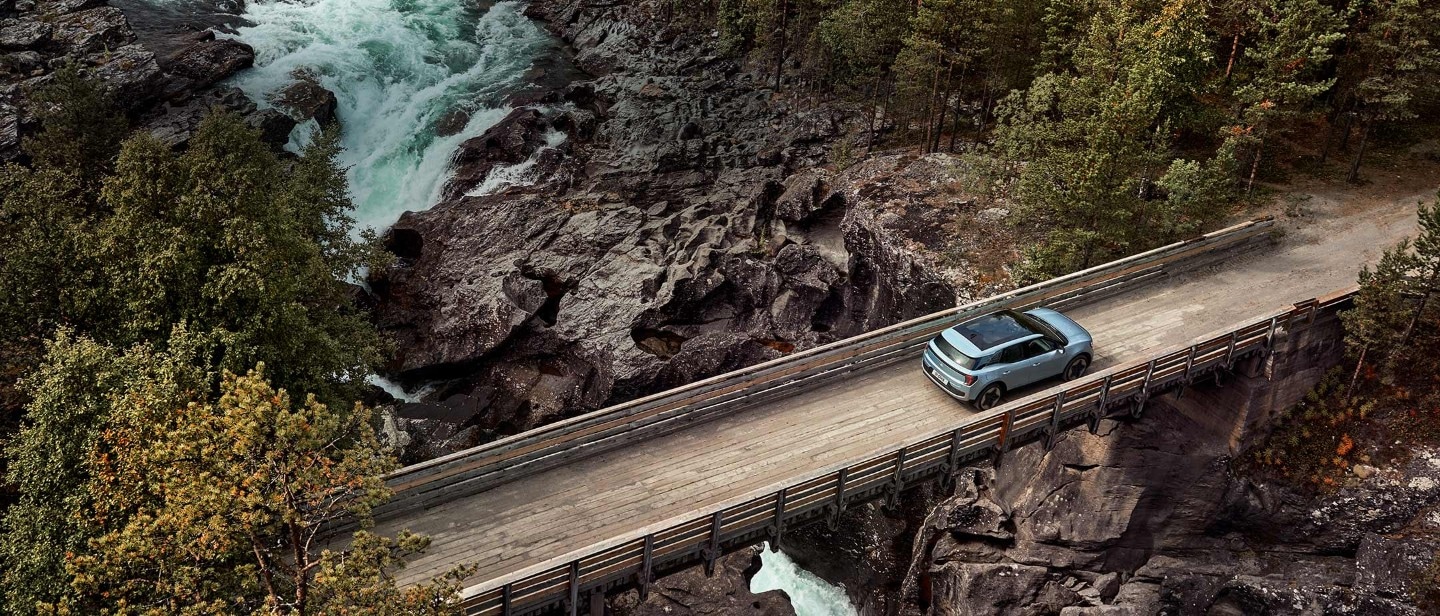 Nuovo Ford Explorer azzurro, vista aerea, in transito su uno stretto ponte di legno sopra un fiume