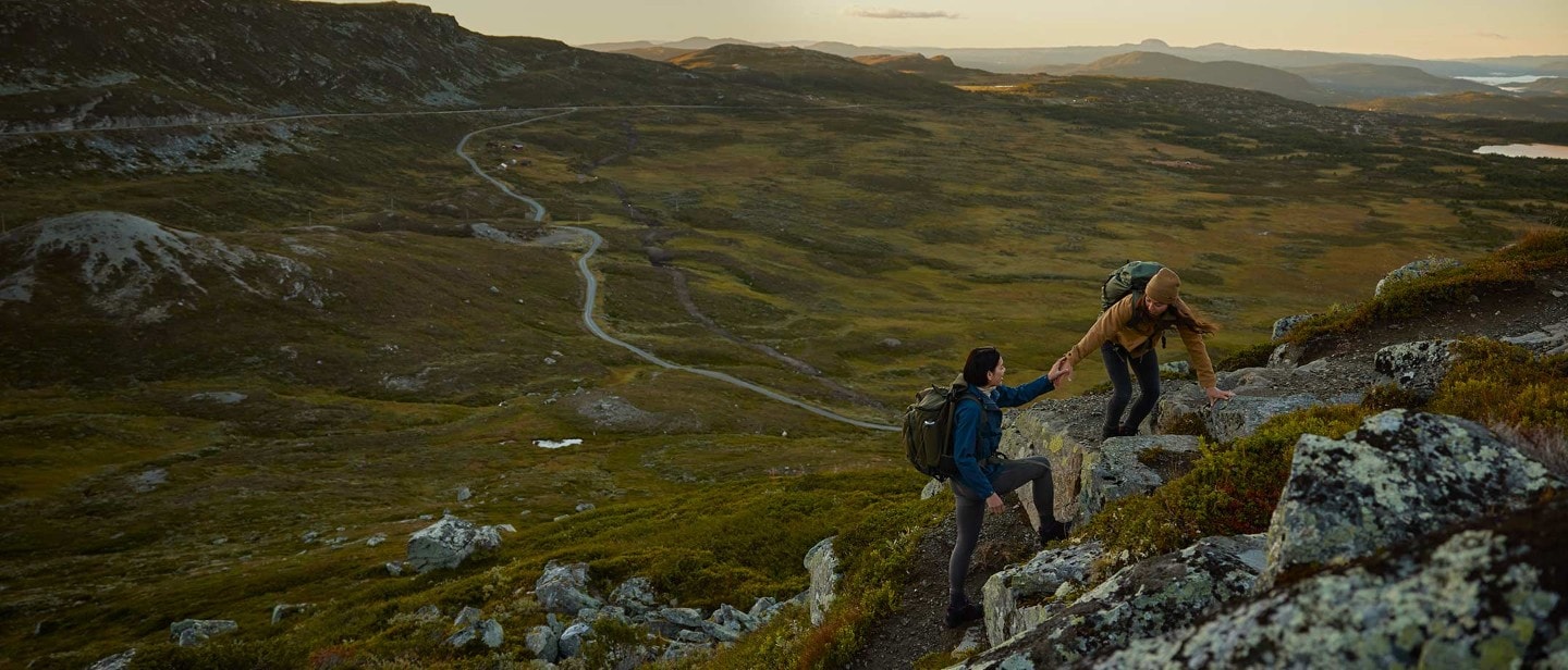 Due donne si aiutano a vicenda a salire su una montagna