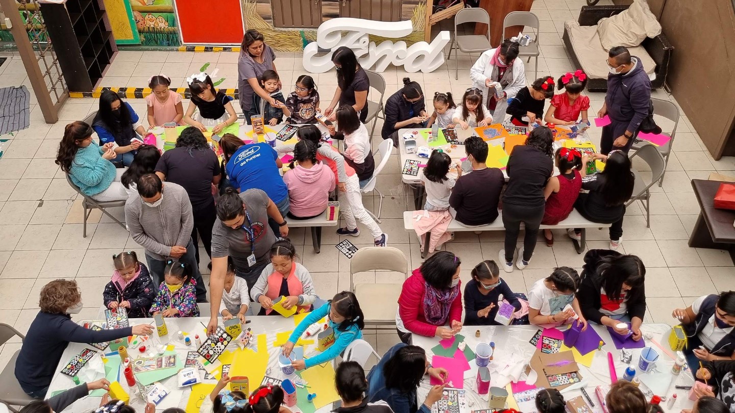 Visuale aerea su un grande gruppo di bambini che fa bricolage insieme a degli educatori