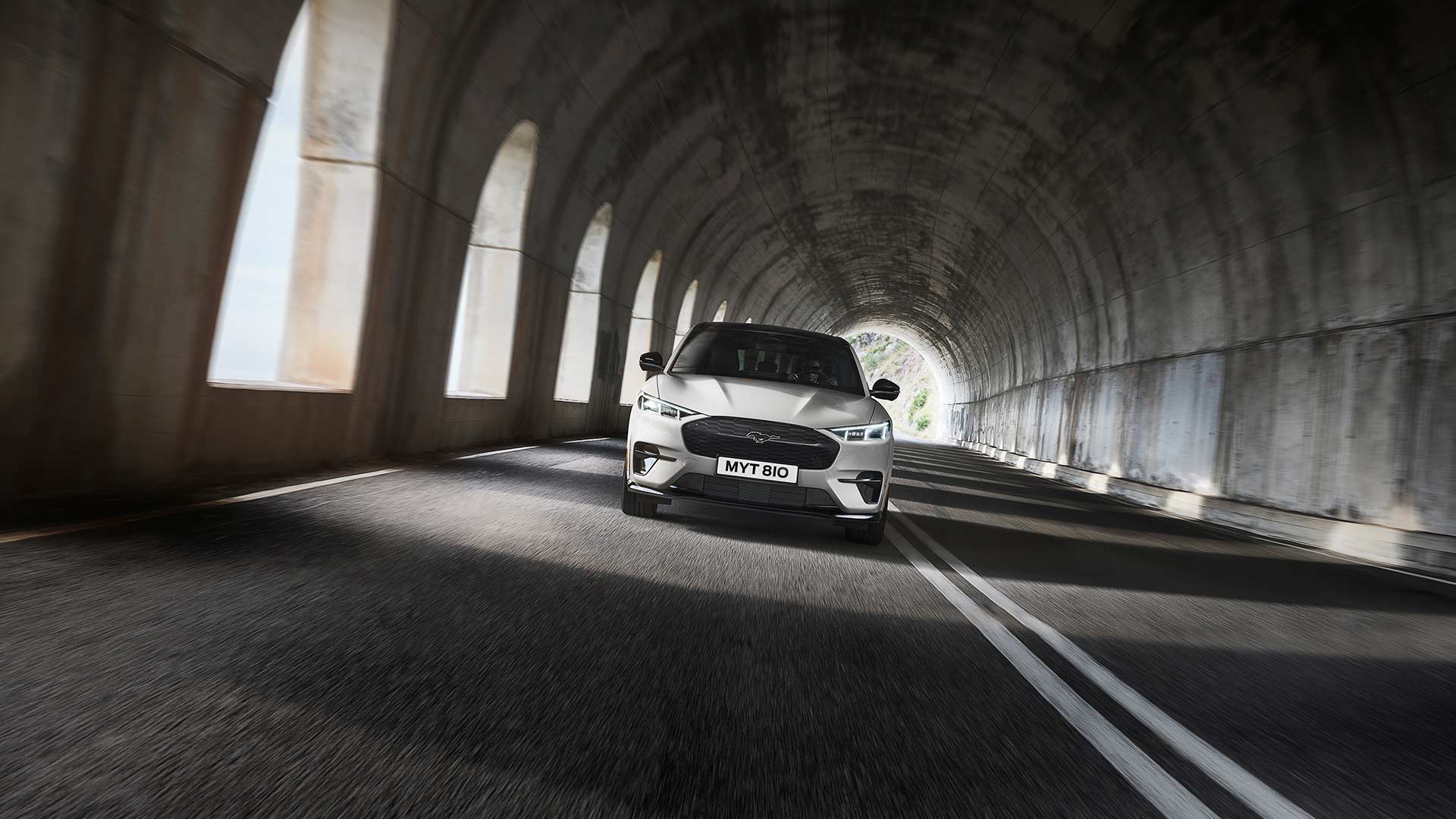 Una Ford Mustang Mach-E elettrica color argento attraversa una galleria.
