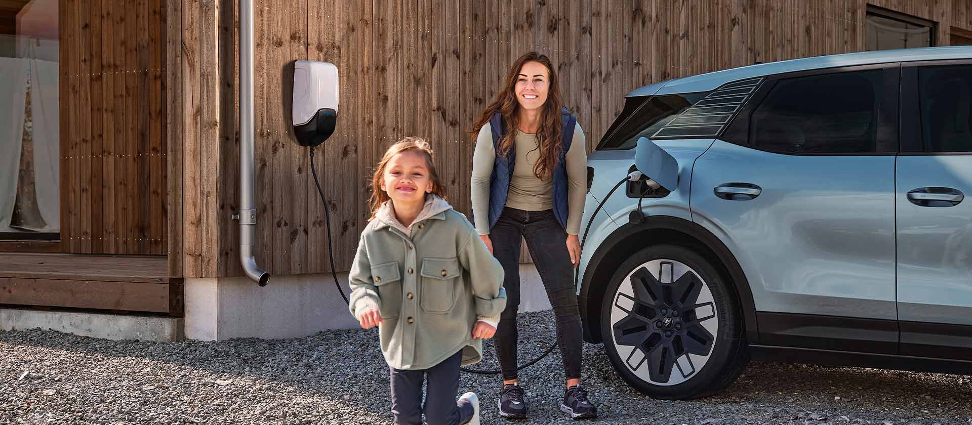 Una famiglia si diverte durante la ricarica del proprio Ford Explorer elettrico tramite una stazione di ricarica per veicoli elettrici.