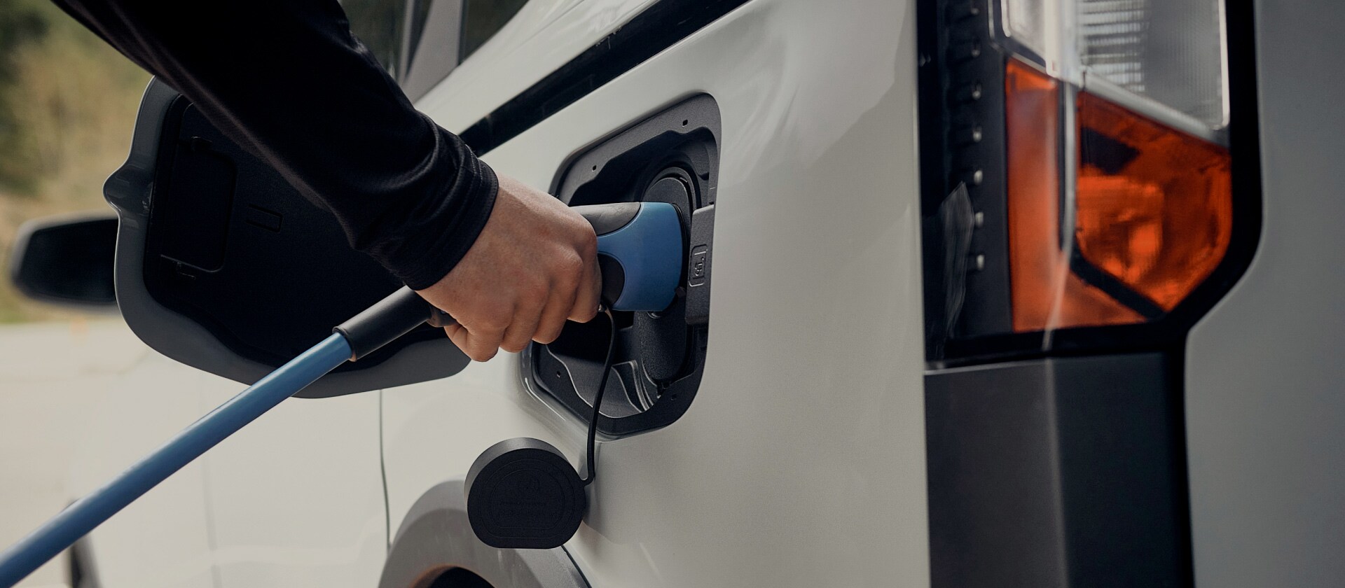 Primo piano di un veicolo elettrico Ford bianco che è collegato a una stazione di ricarica per veicoli elettrici.