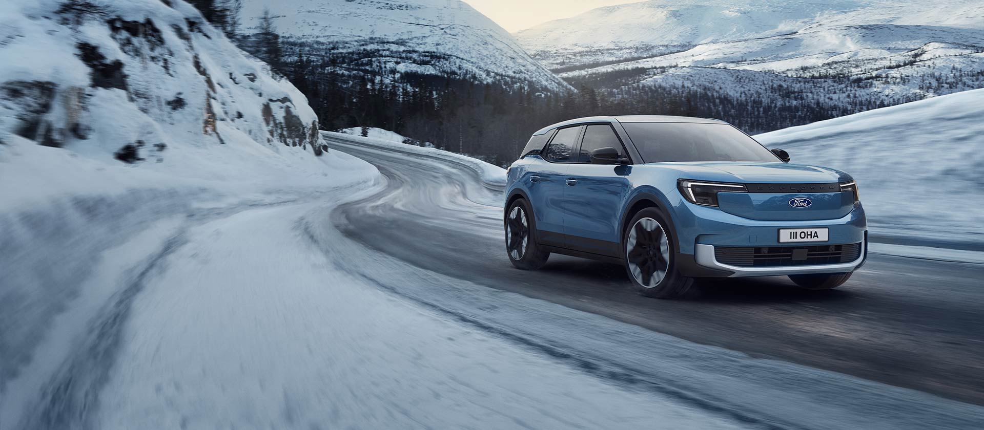 Ford Explorer elettrico blu su una strada di montagna innevata per rappresentare la potenza e l’autonomia in inverno.