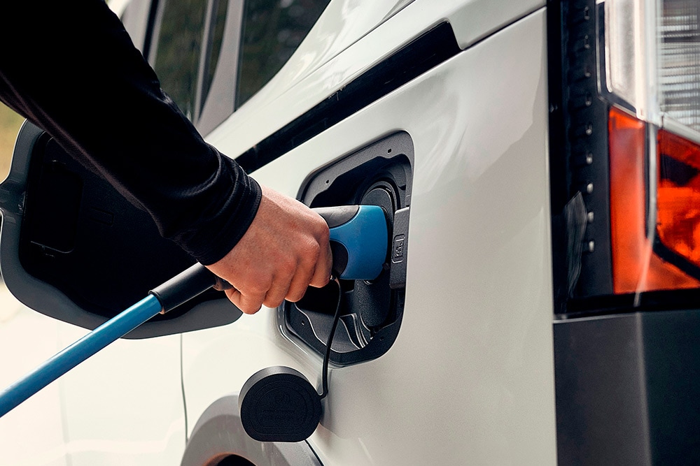 Una persona collega un cavo di ricarica per veicoli elettrici a un veicolo elettrico Ford.
