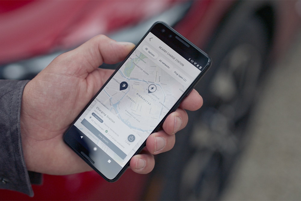 Uno smartphone mostra l’app FordPass™ con le stazioni di ricarica pubbliche per veicoli elettrici Ford nelle vicinanze.