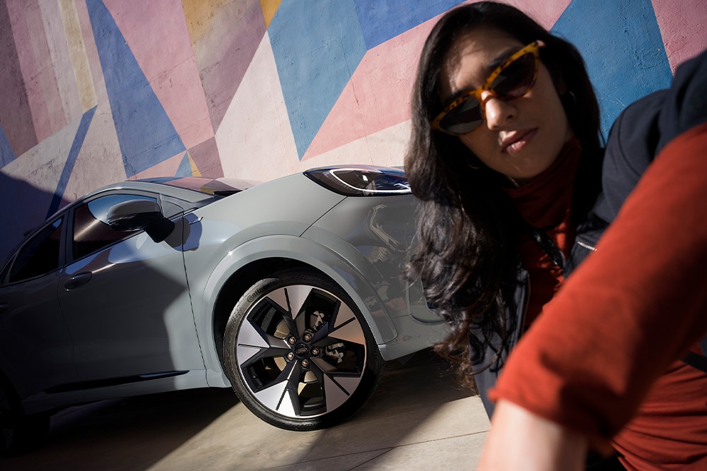 Una persona seduta accanto a una Ford Puma Mild Hybrid.