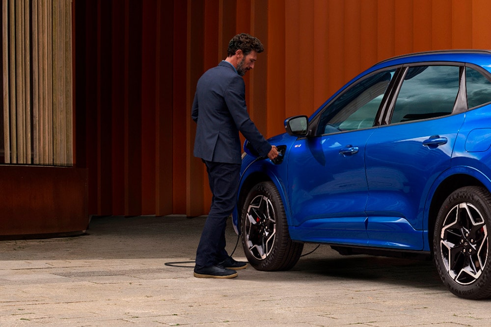Una persona collega un veicolo Plug-in-Hybrid Ford a un impianto di ricarica.