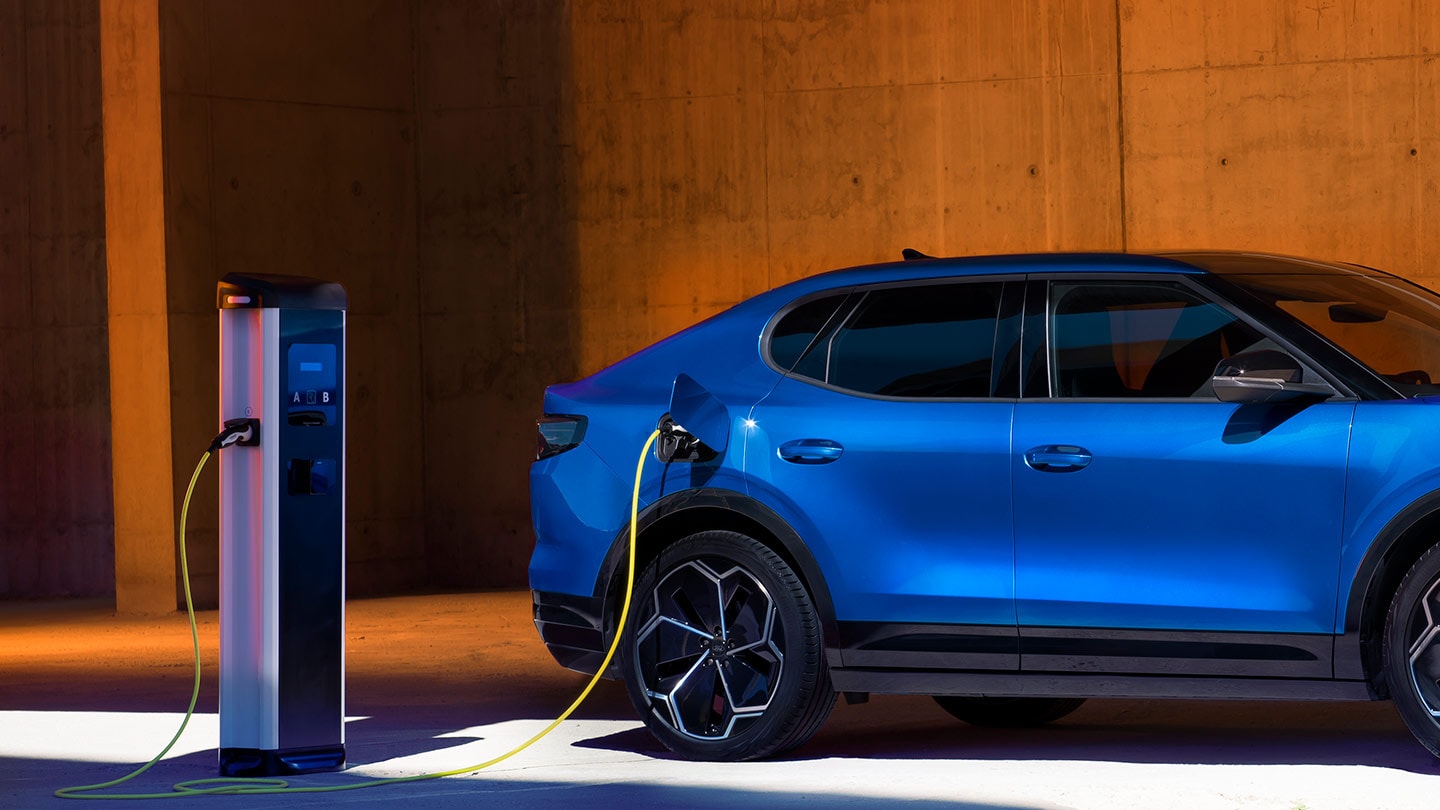 Una Ford Capri elettrica blu collegata a una stazione di ricarica per veicoli elettrici.