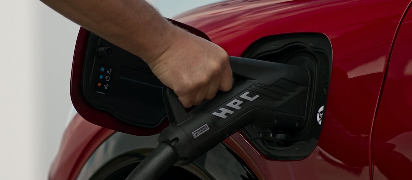 Primo piano di un veicolo elettrico Ford rosso che è collegato a una stazione di ricarica pubblica per la ricarica rapida.