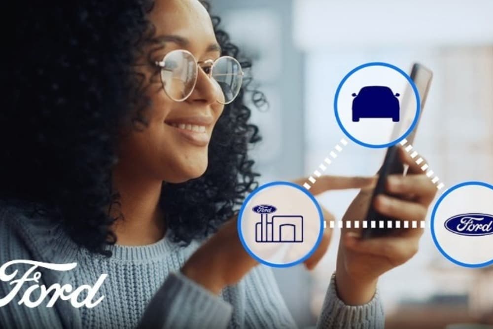 A close up of a hand holding a smartphone and interacting with the Ford app