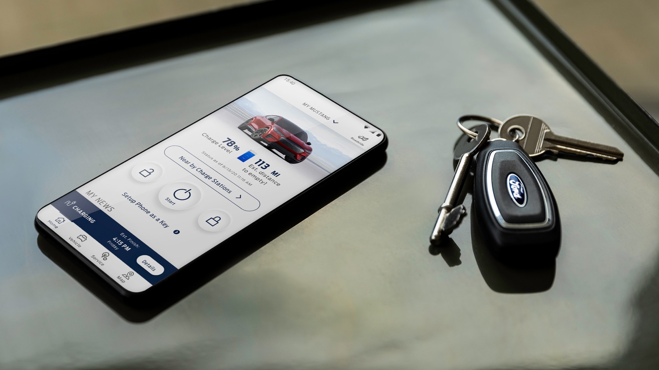Un telefono sul cui schermo compare l’app FordPass è appoggiato su una scrivania accanto ad alcune chiavi auto 