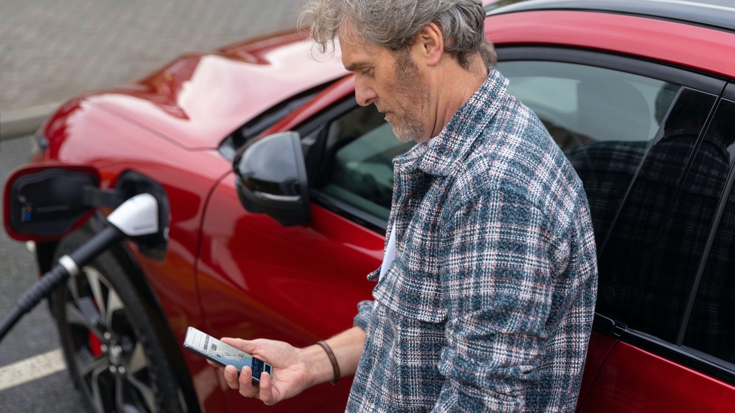Un uomo guarda il proprio smartphone mentre l’auto si carica