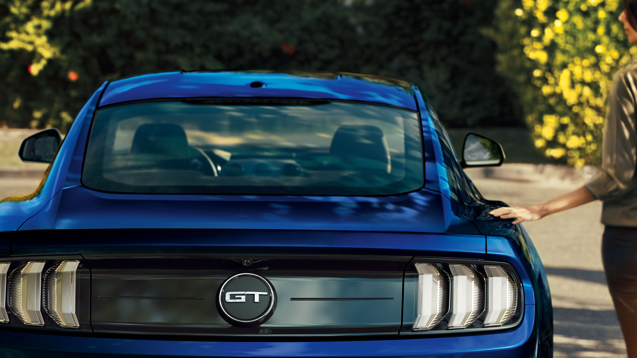 Ford Mustang GT blu. Vista posteriore, con una donna accanto