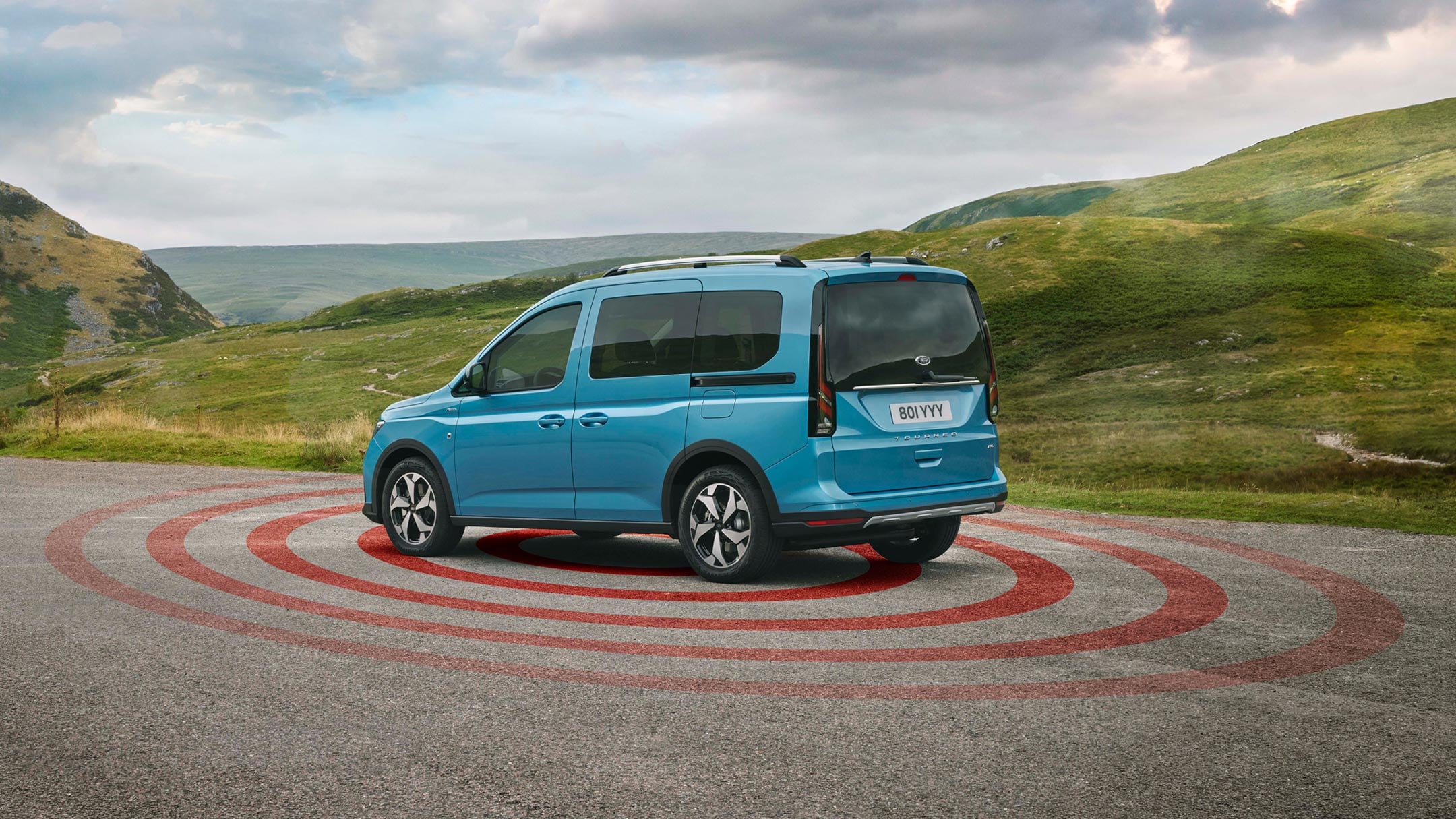 Ford Tourneo Connect rosso, vista frontale a tre quarti, parcheggiato in un vialetto ghiaioso davanti a una casa, con illustrazione dell’impianto d’allarme antifurto