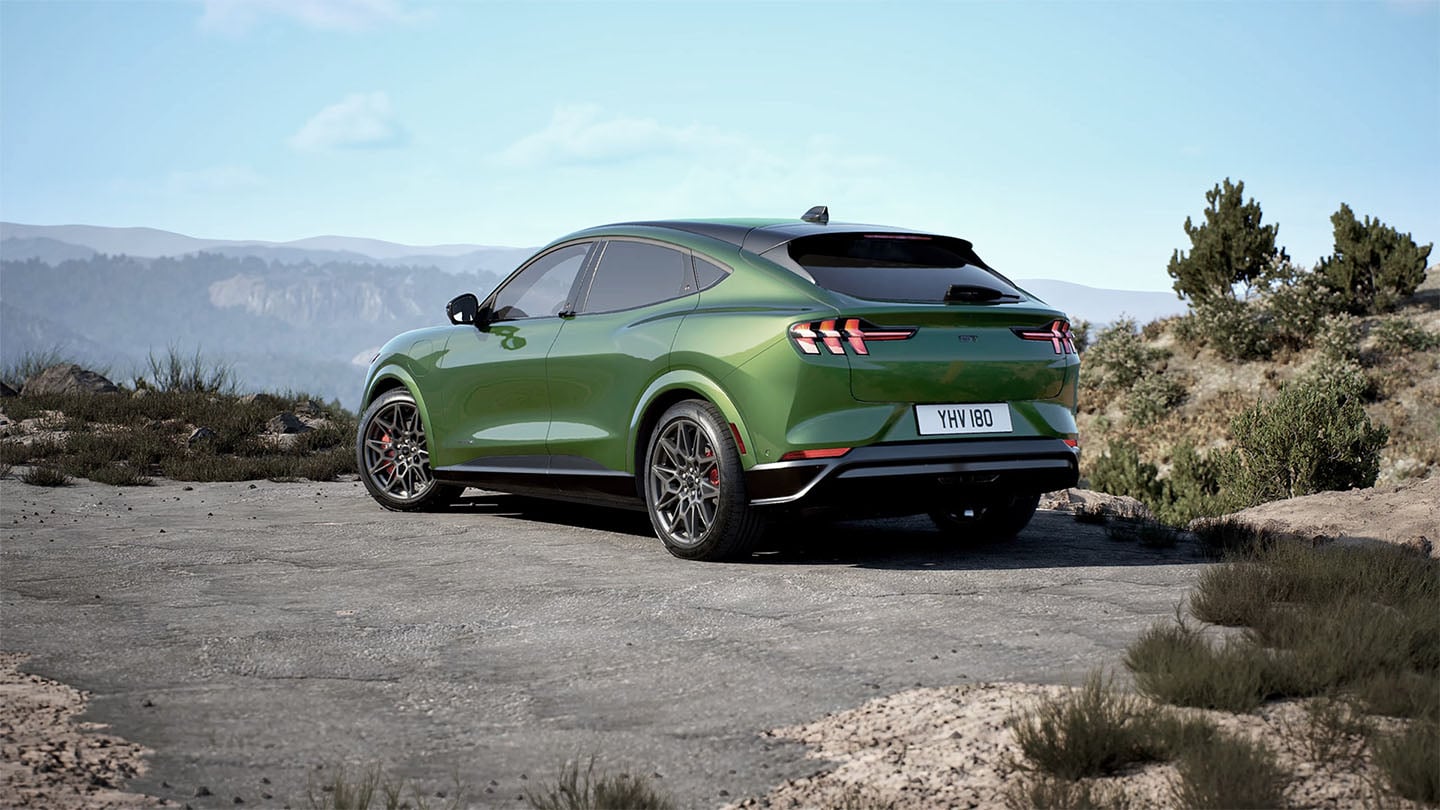Vista posteriore di una Ford Mustang Mach-E GT verde parcheggiata su una strada di montagna.