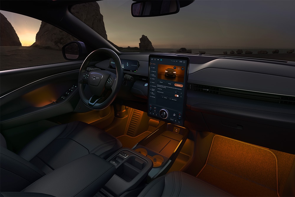 Ford Mustang Mach-E di notte, con il touchscreen SYNC 4 da 15.5 pollici e l’illuminazione ambiente a LED impostata sull’arancione.