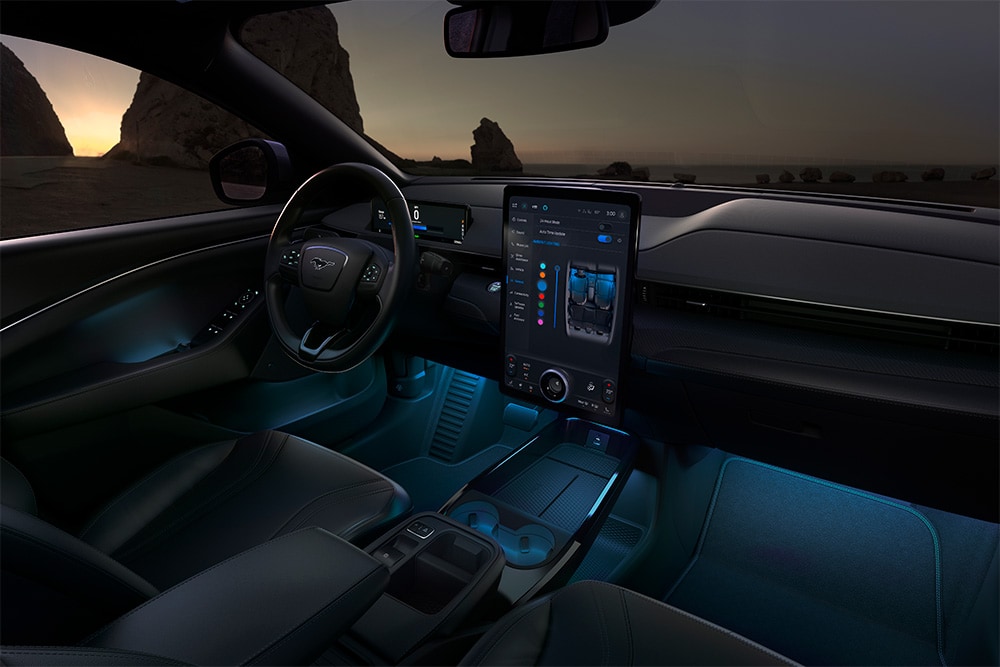 Ford Mustang Mach-E di notte, con il touchscreen SYNC 4 da 15.5 pollici e l’illuminazione ambiente a LED impostata sul blu.