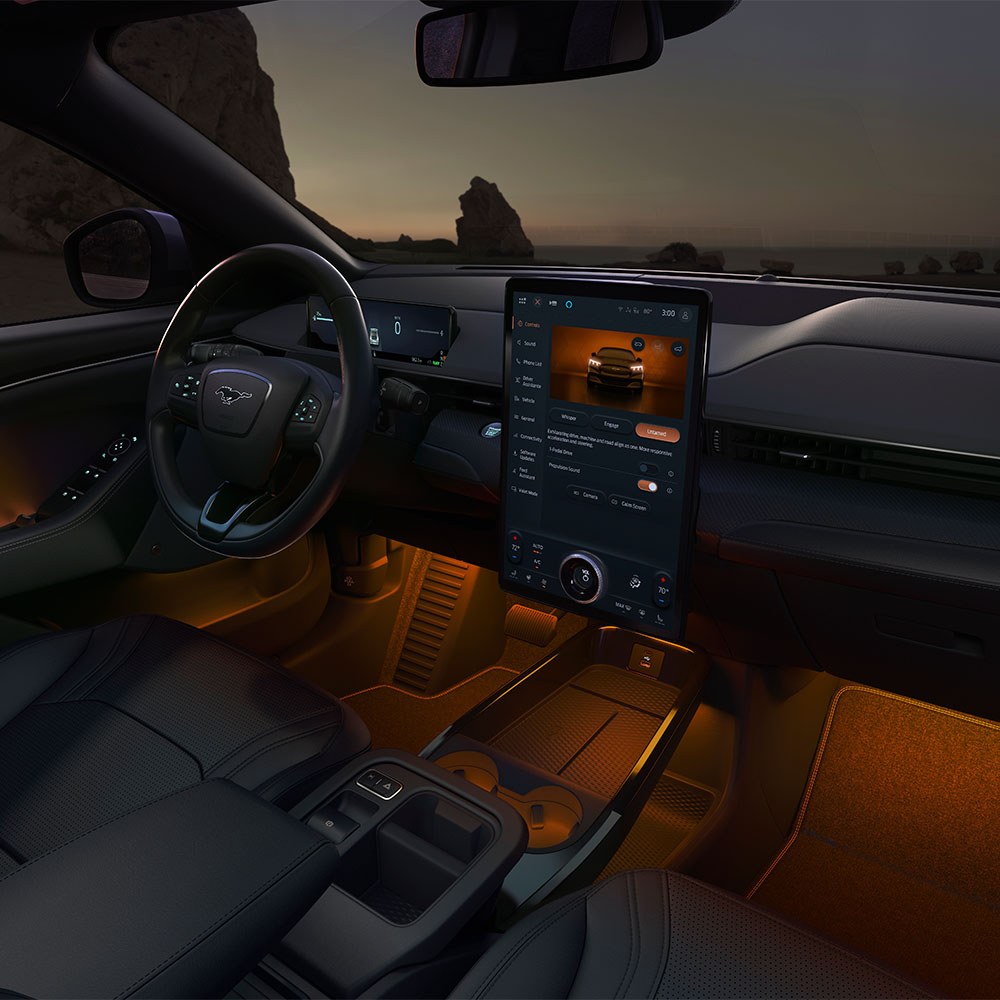 Ford Mustang Mach-E di notte, con il touchscreen SYNC 4 da 15.5 pollici e l’illuminazione ambiente a LED impostata sull’arancione.