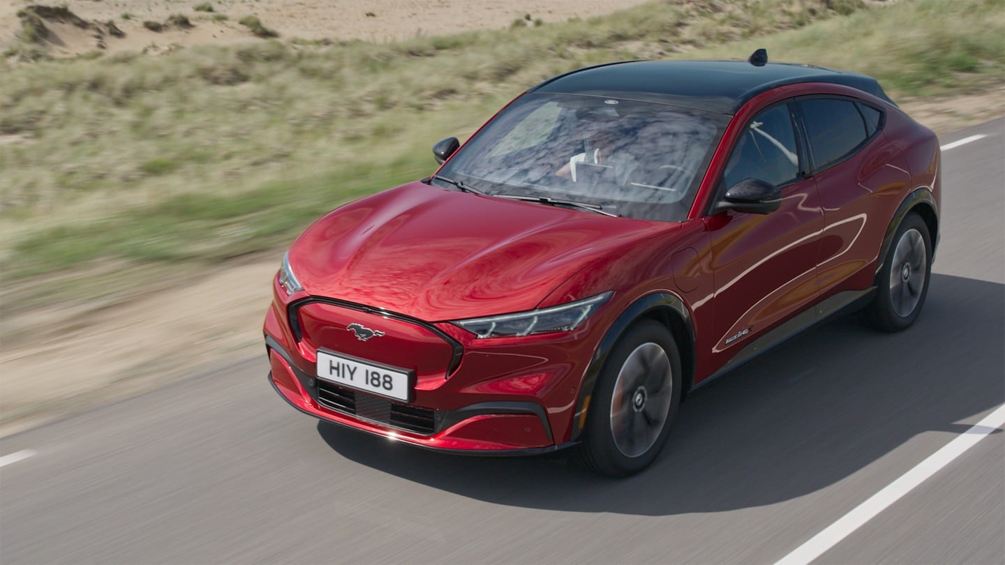 Ford Mustang Mach-E rossa. Vista frontale a tre quarti. AWD con ambientazione su strada extraurbana