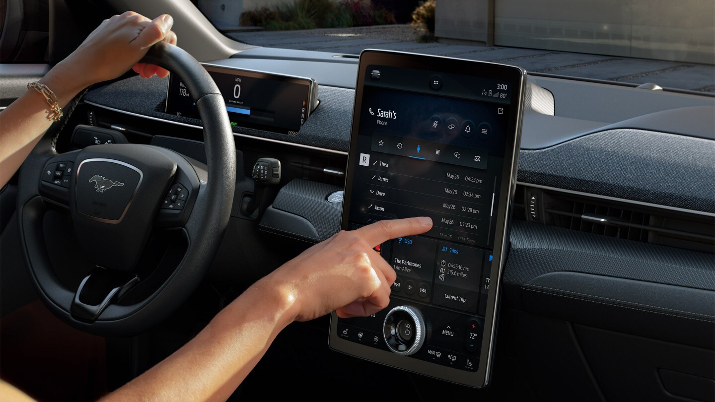 Ford Mustang Mach-E. Dettaglio di come la mano del guidatore aziona il Ford SYNC 4A Touchscreen.