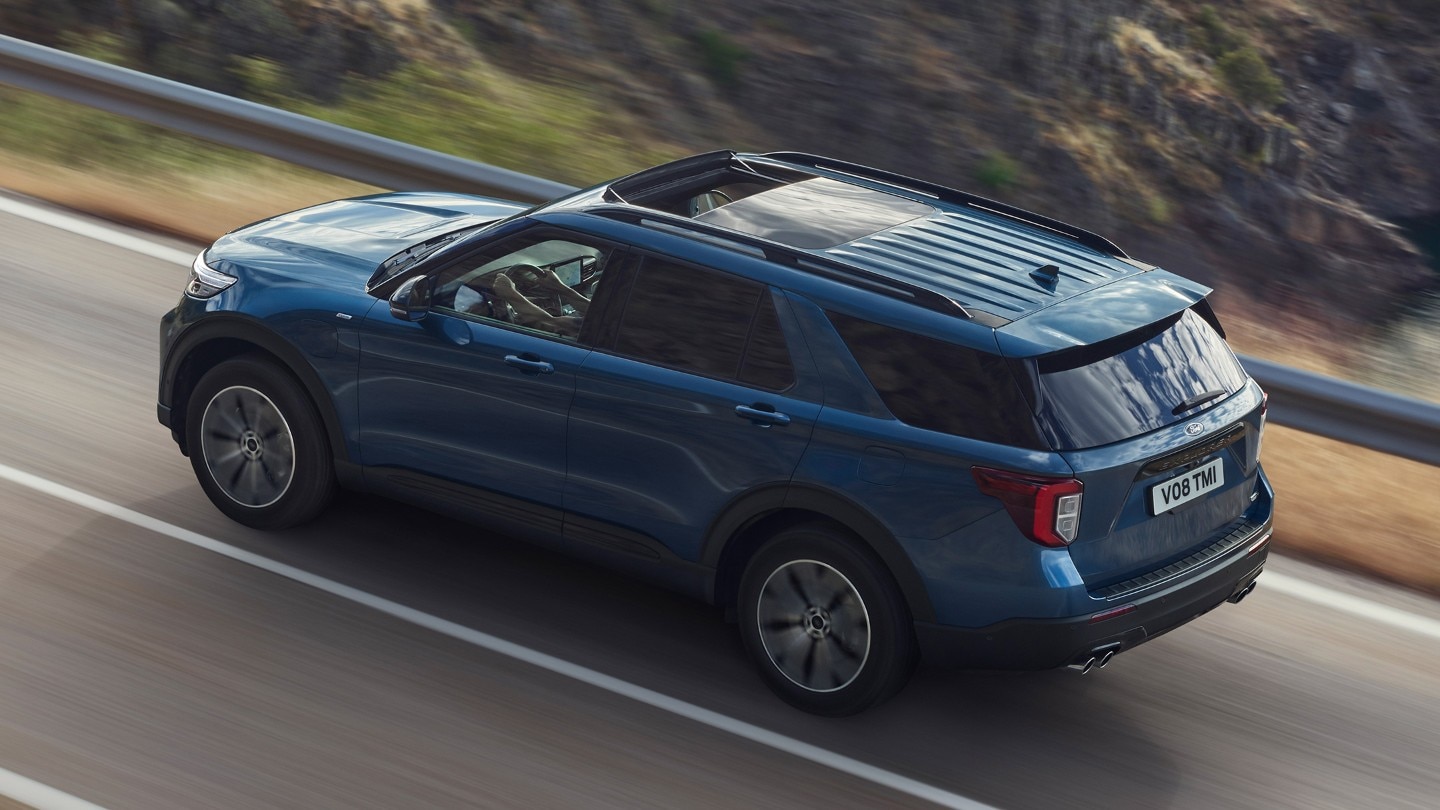 Ford Explorer in versione blu. Visuale posteriore in 3/4. Guida su una strada in salita verso le montagne
