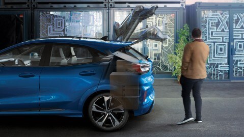 Ford Puma grigia, vista laterale ravvicinata, con un uomo che apre con un movimento del piede il portellone posteriore dotato di sensori