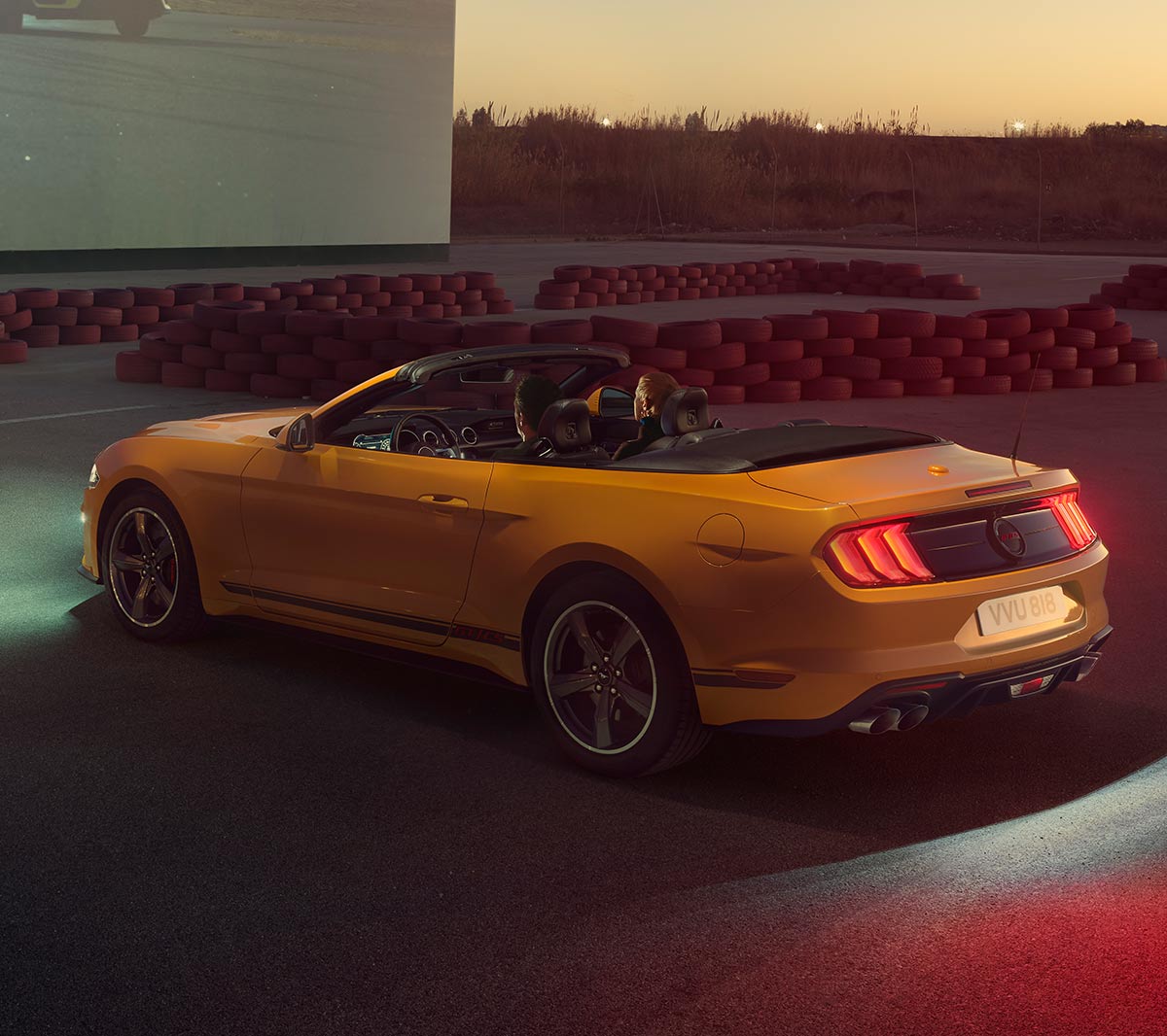 Ford Mustang GT in movimento che guida sulla strada sopra un villaggio rurale