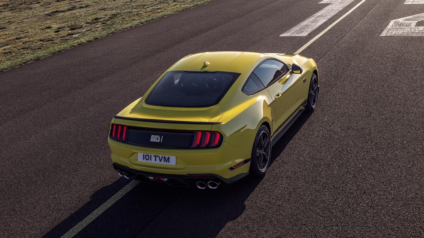 Ford Mustang Mach-E gialla. Vista posteriore a tre quarti, in marcia su un circuito