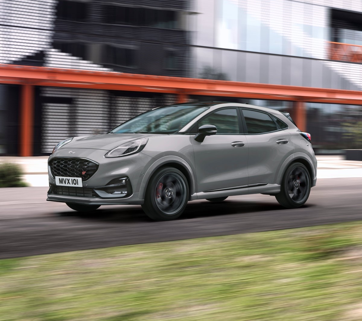 Ford Puma ST grigia, vista frontale a tre quarti, su una strada davanti a un edificio moderno