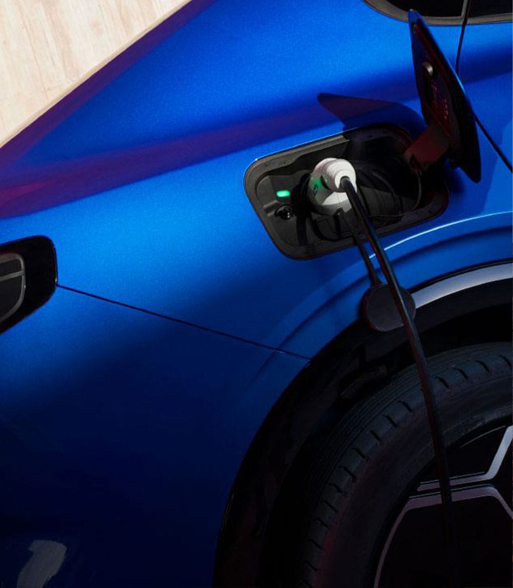 Una Ford blu è in carica, con un cavo di ricarica inserito nella porta aperta.