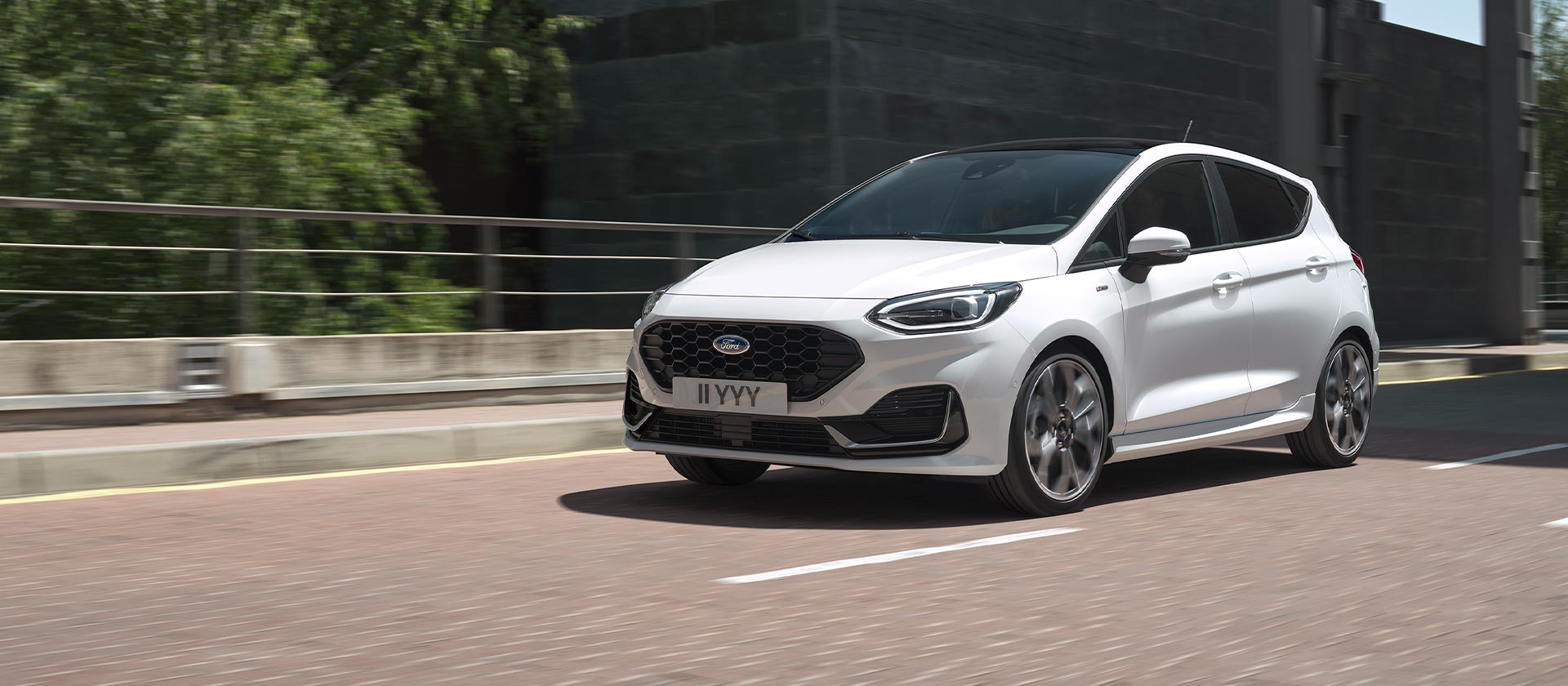 Una Ford Fiesta bianca circola in una città.