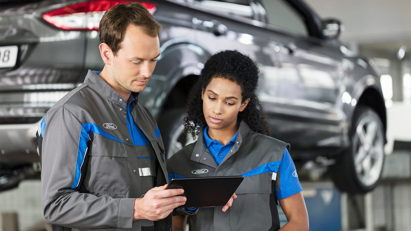 Due specialisti di riparazioni Ford verificano al tablet il sistema di prenotazione online del servizio.