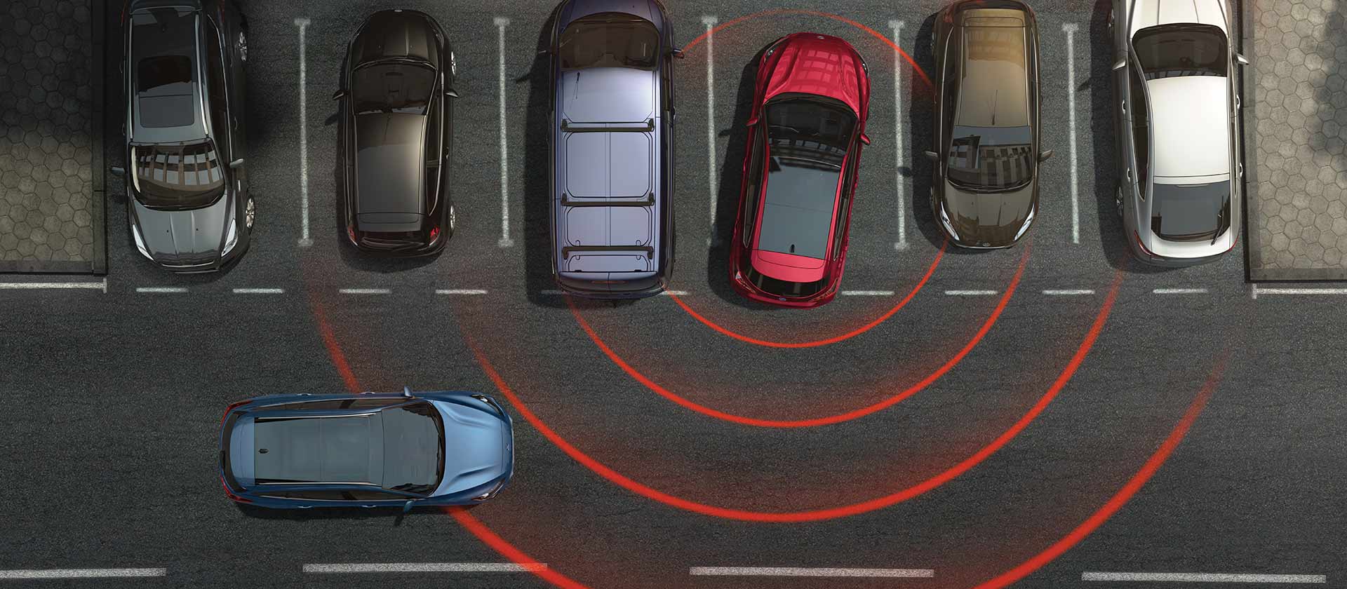 Immagine grafica dall’alto di una serie di posteggi. In una Ford Focus rossa in uscita dal parcheggio in retromarcia, linee virtuali allertano il conducente evidenziando la presenza di una vicina fonte di pericolo.