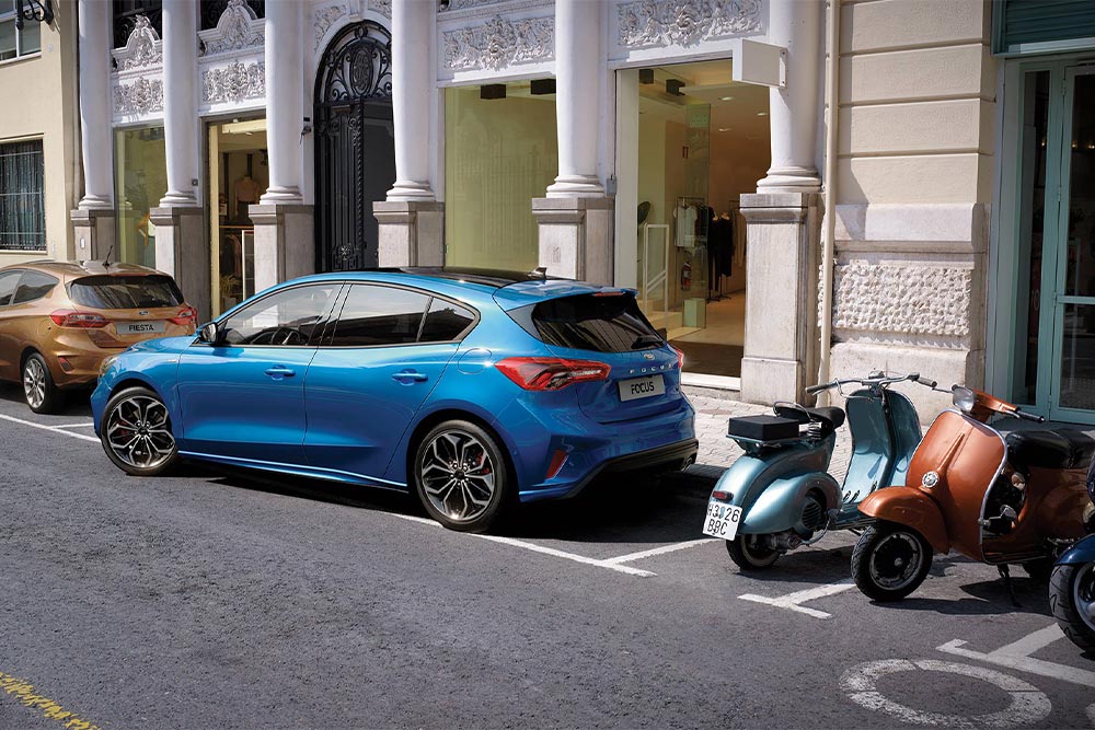 Una Ford Focus blu parcheggia in un posteggio in città con l’aiuto dell’assistente di parcheggio attivo.