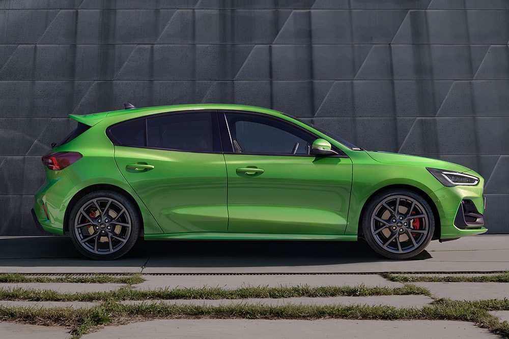 Vista laterale di una Ford Focus ST modello hatchback color Mean Green, ferma di lato, oltre la strada.