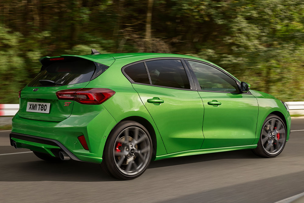 Vista posteriore di una Ford Focus ST modello hatchback color Mean Green, in corsa su un circuito di gara.