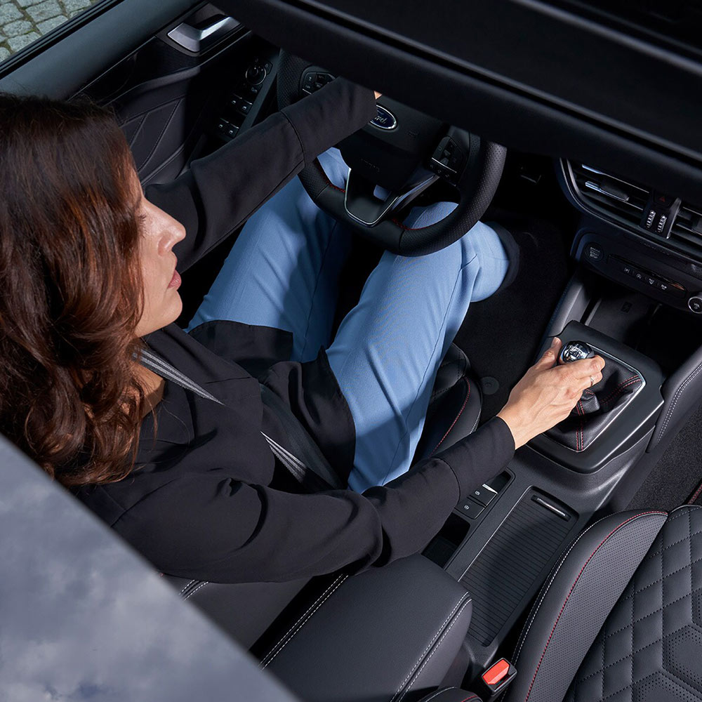 Vista dall’alto su una persona che guida una Ford Focus, ripresa attraverso il tetto panoramico in vetro.