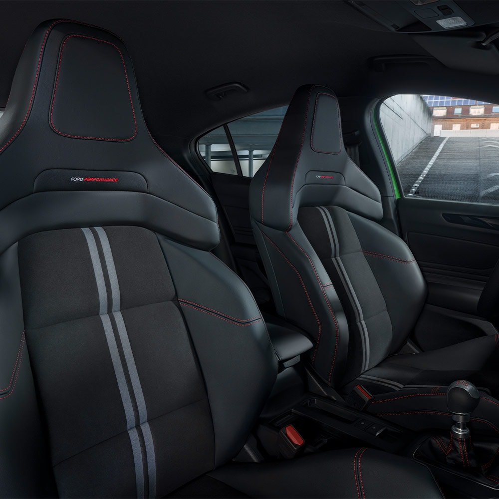 Vista ravvicinata dei sedili sportivi della Ford Focus ST con rivestimenti scuri e cuciture a contrasto rosse.