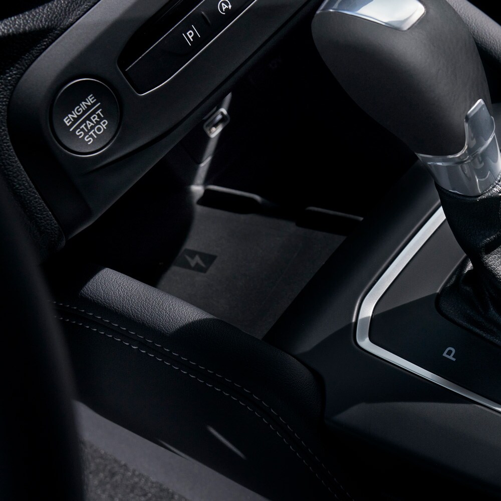 Vista ravvicinata dell’abitacolo di una Ford Focus con dispositivo di ricarica senza fili per smartphone dietro la leva del cambio.
