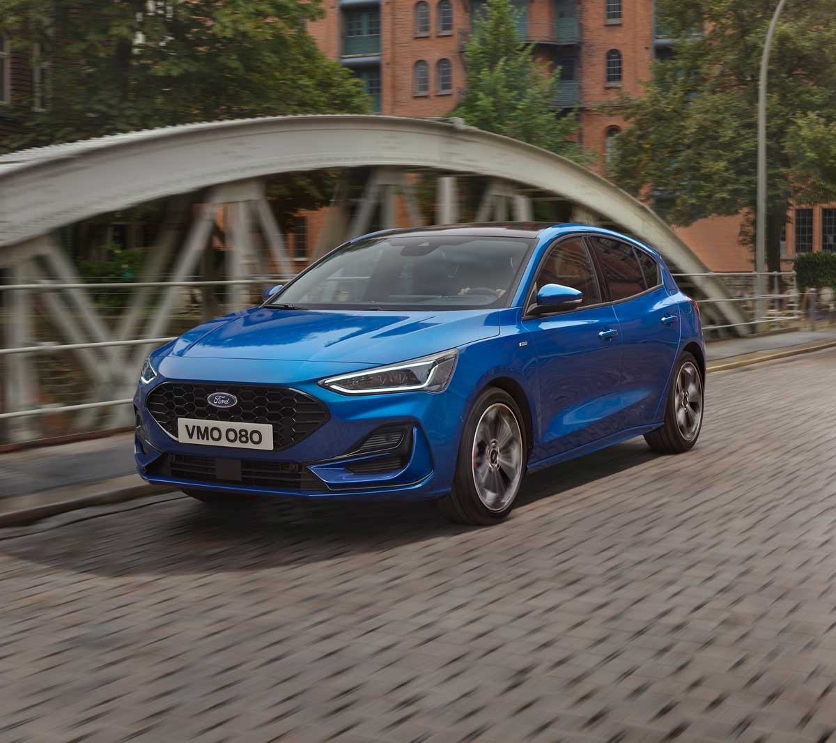 Ford Focus ST-Line blu. Vista frontale a tre quarti, in marcia su un ponte.