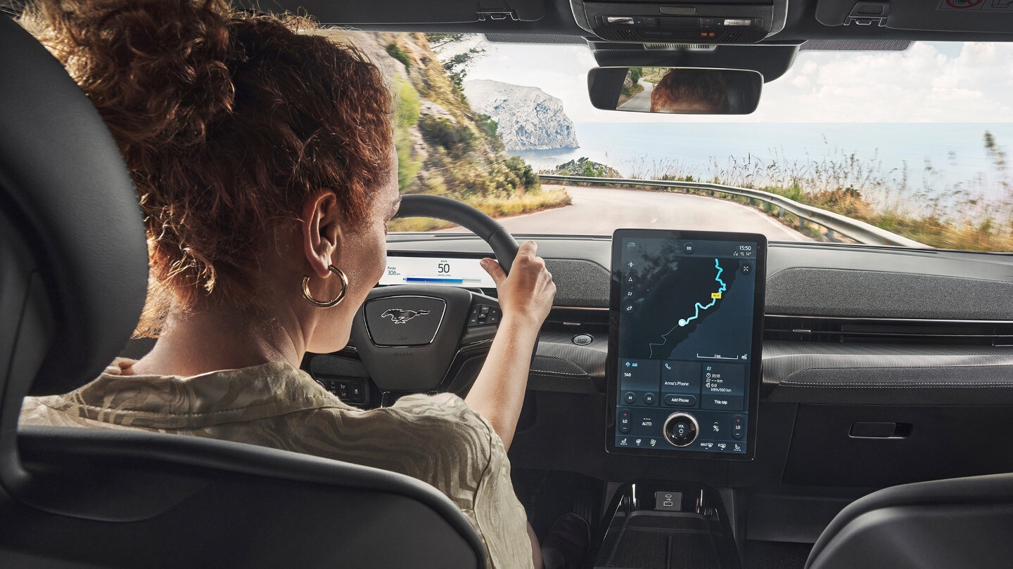 Ford Mustang Mach-E GT. Vista interna, una donna e un uomo guardano il touchscreen del Ford SYNC 4.