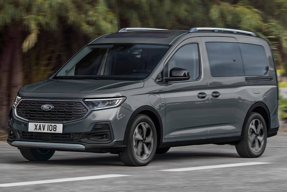 Ford Tourneo Connect grigio, vista frontale a tre quarti, in transito su una strada di montagna con fiume sullo sfondo
