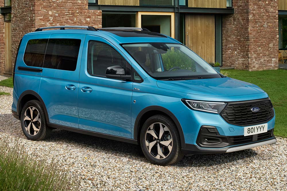 Ford Tourneo Connect azzurro, vista frontale a tre quarti, parcheggiato in un vialetto ghiaioso davanti a una casa